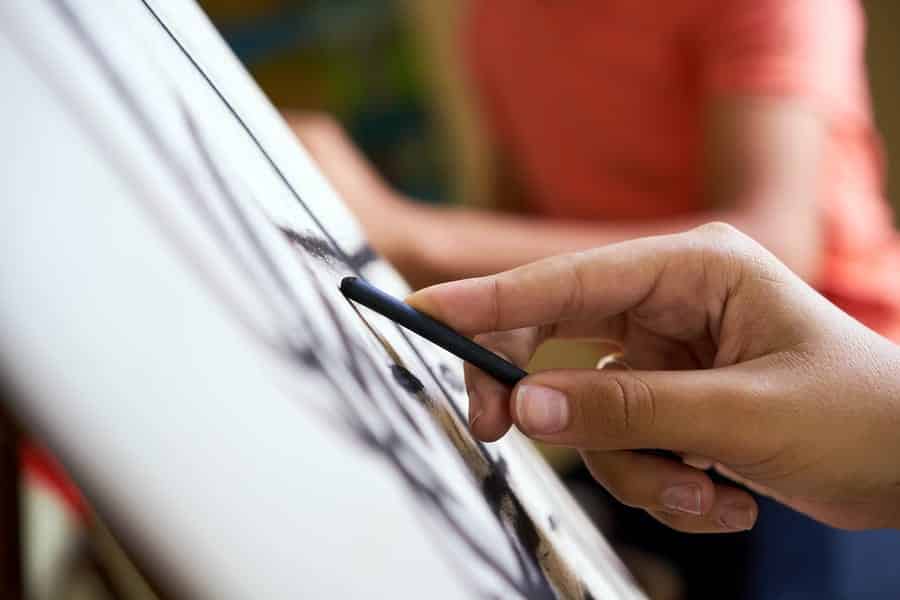 A photo of a person shading a sketch with charcoal.