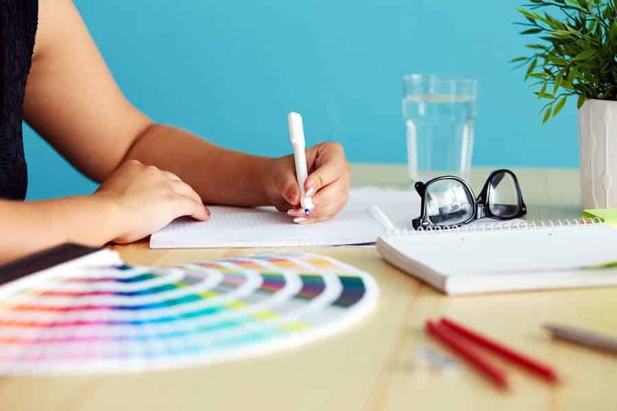 A photo of a graphic designer whipping up some sketches with a color fan spread out next to her.