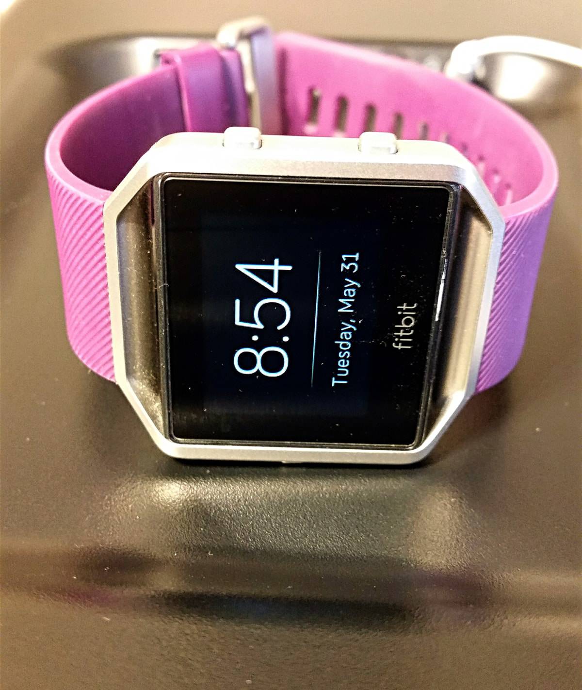 A photo of a Fitbit Blaze with a pink wristband sitting on a table.