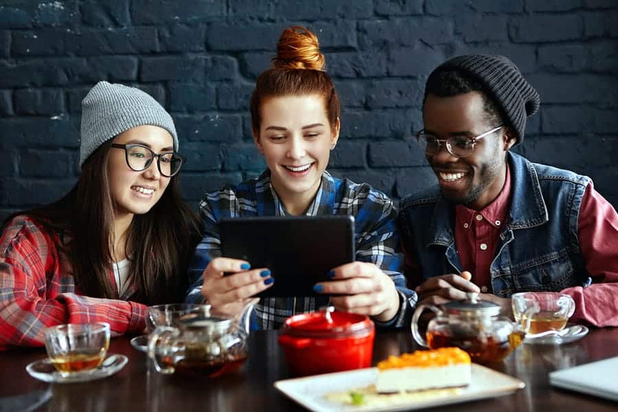 A photo of three people studying mobile app ux design on a tablet.