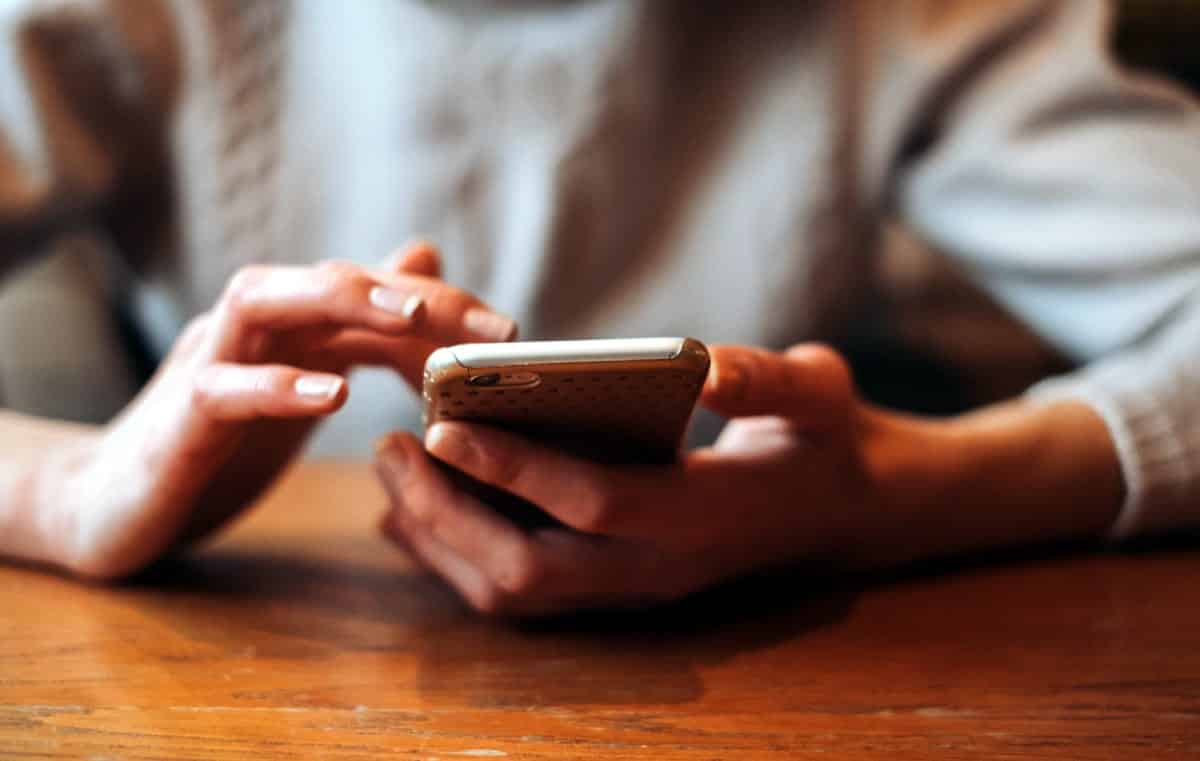 A photo of a woman at a desk using an iPhone.