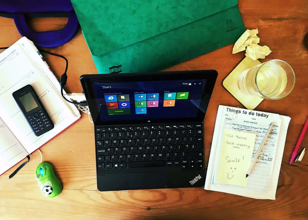 A photo of someone’s kitchen table turned into a makeshift office, complete with a laptop and office supplies.