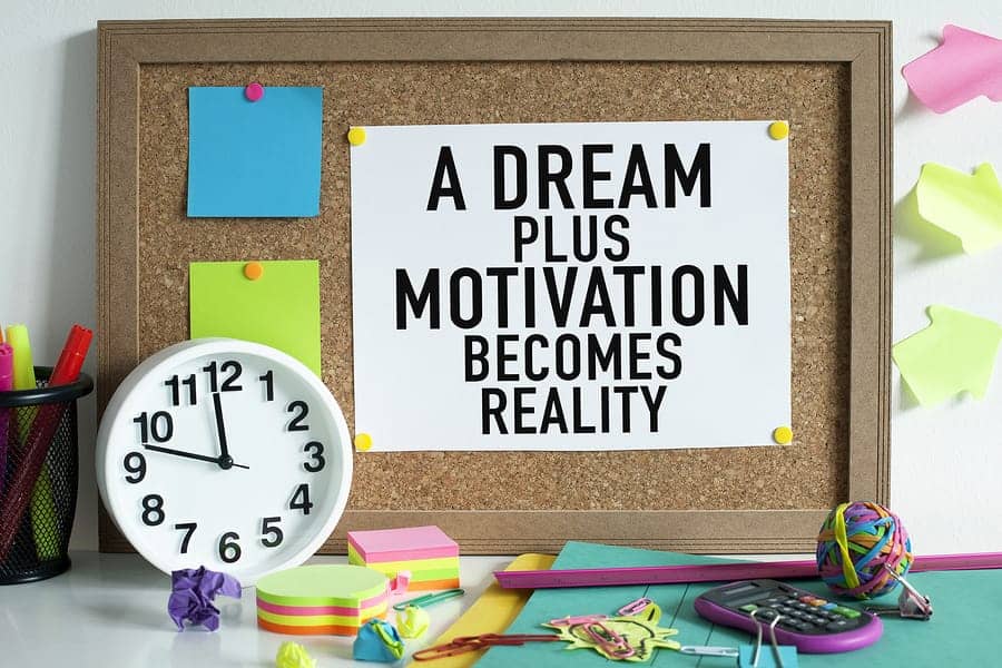 A photo of a corkboard with a motivational message, saying “A dream plus motivation becomes reality.”