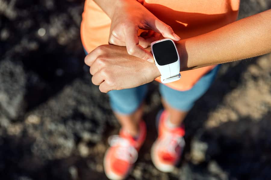 A photo of a woman checking her wearable prior to starting a run.