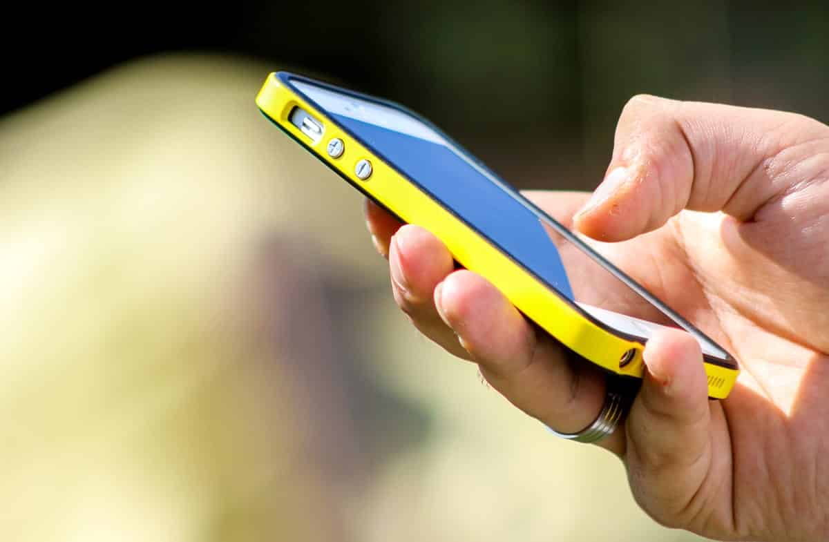 A photo of a person holding an iPhone in a bright yellow case.
