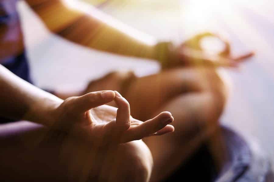 A close-up photo of someone’s hands while sitting in meditation.