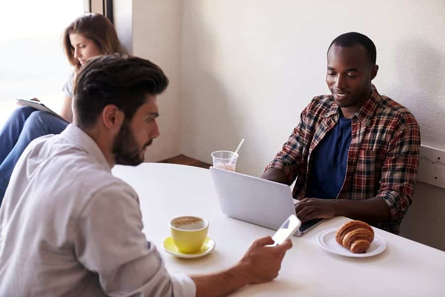 A photo of three people sitting near each other, but working separately in a coffee shop.