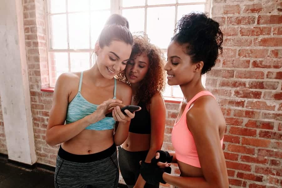 A photo of three women looking at something on a smartphone.