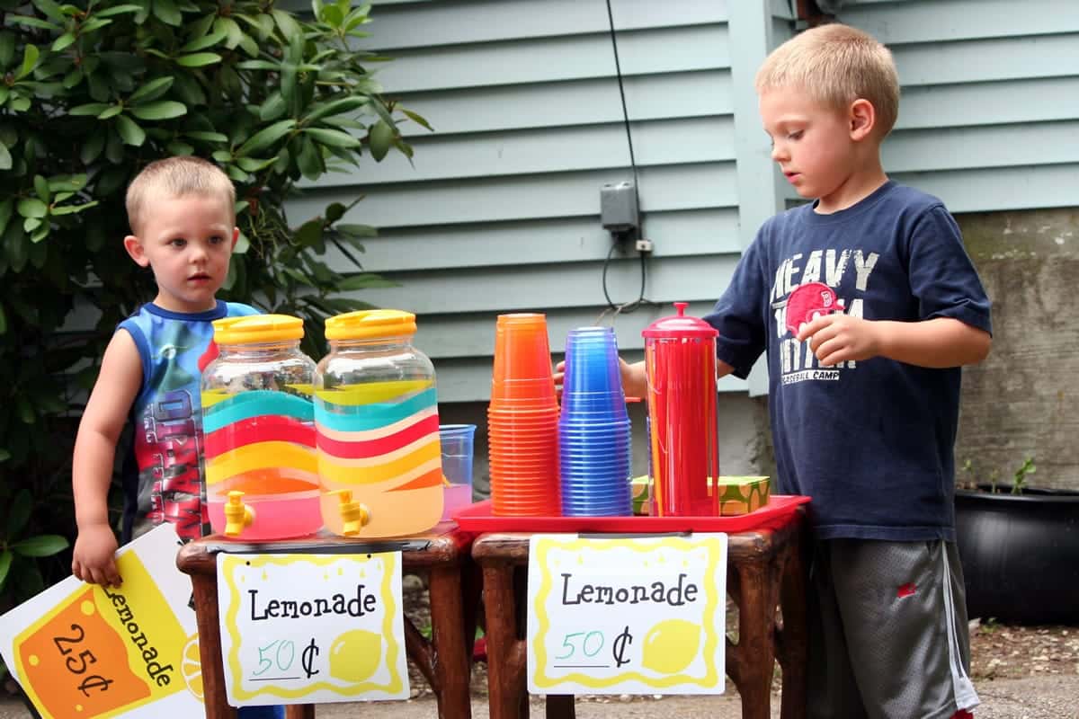 A photo of two young boys setting up a lemonade stand.