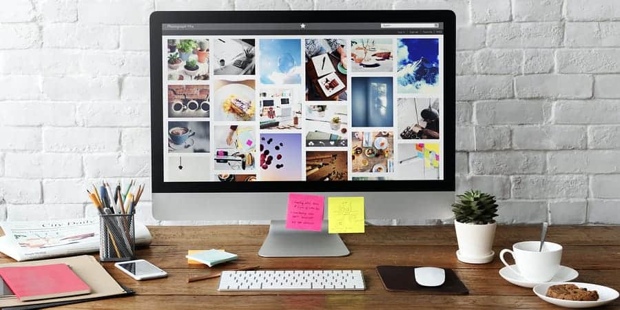 A photo of a designer’s desk, complete with a large computer monitor, coffee, and a cookie.