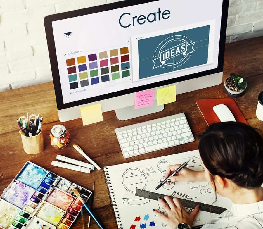 A photo of a graphic designer drawing on a notepad at her desk.