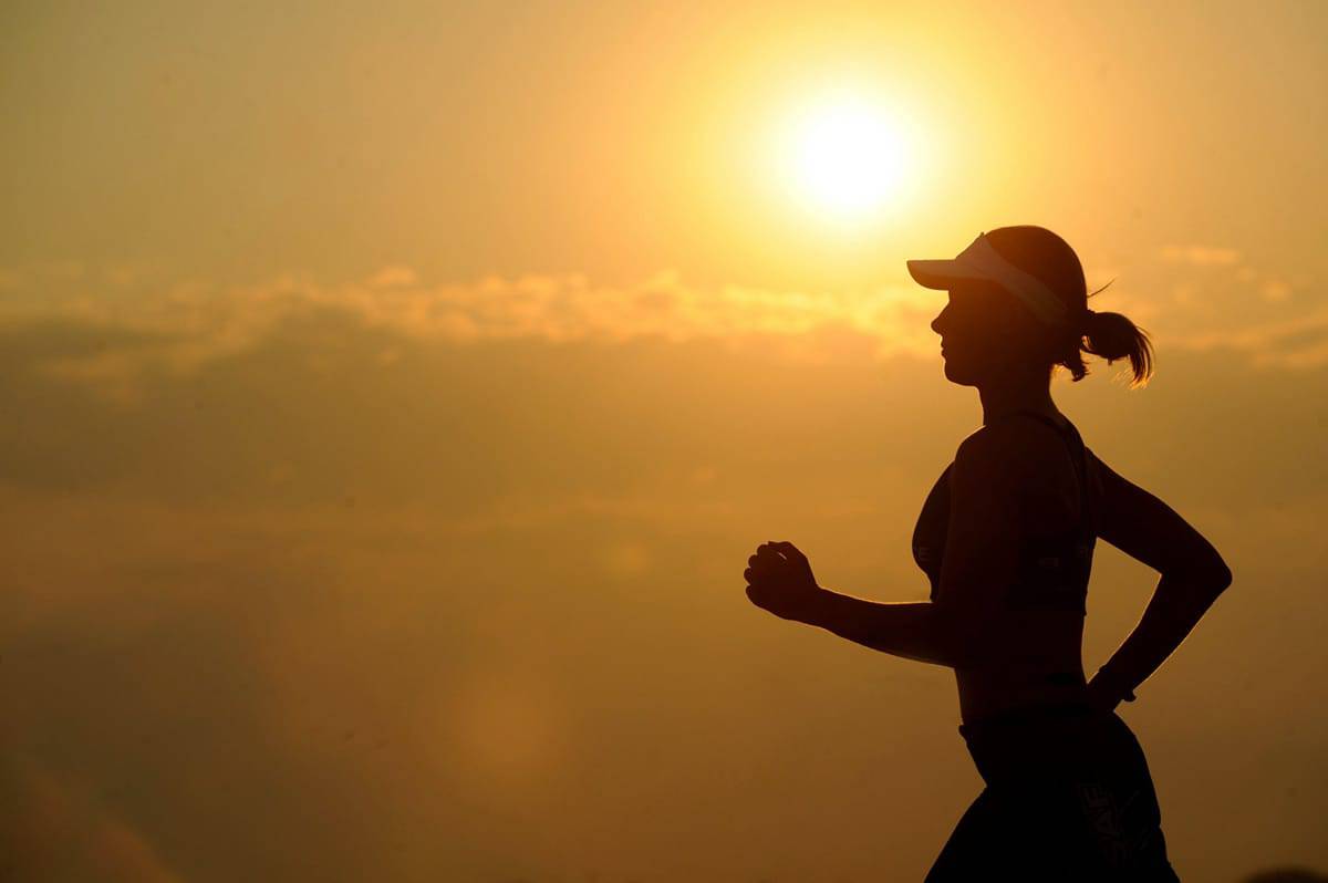 An image of a woman on a run at sunset.