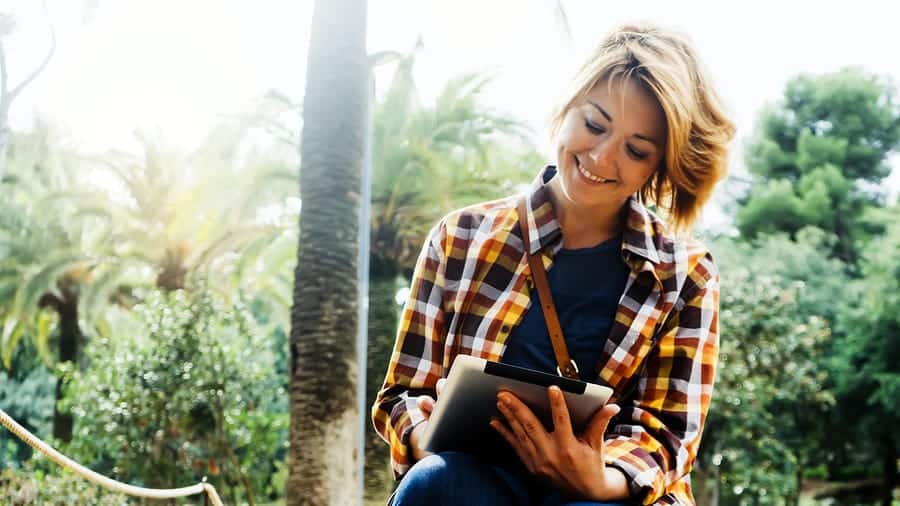 A photo of a smiling young woman holding a tablet.