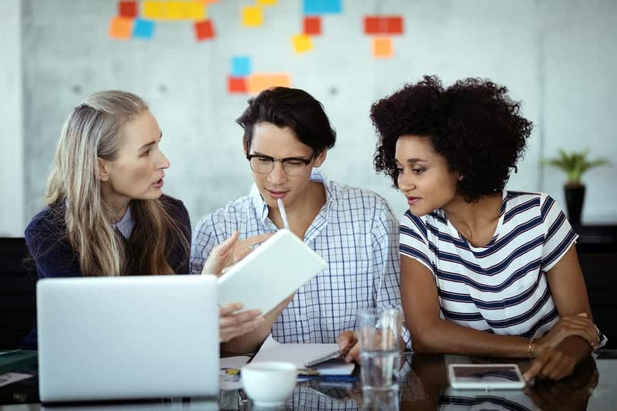 A photo of three people gathered at a table for a meeting