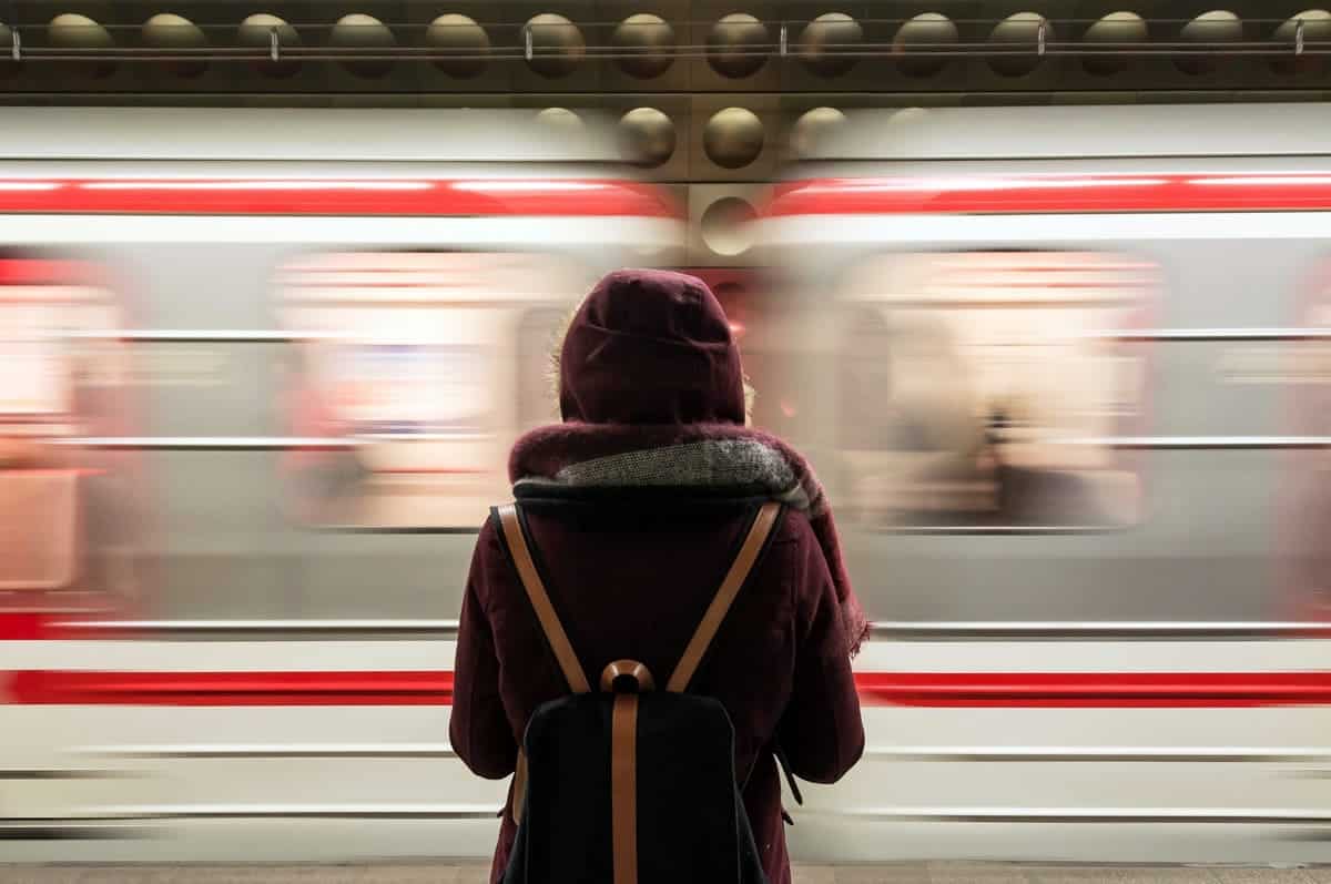 An image of a person waiting for the train at the station as it speeds by.