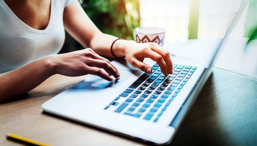 A photo of a woman typing on her laptop in a brightly lit office.