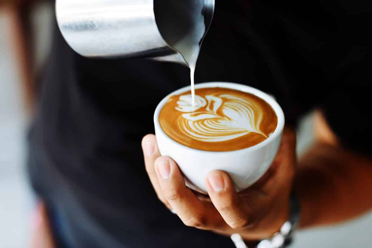 An image of a person making a latte at a cafe.