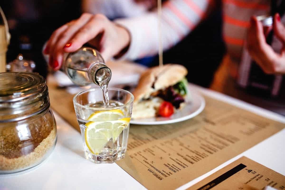 An image a woman pouring water into her glass at lunch.