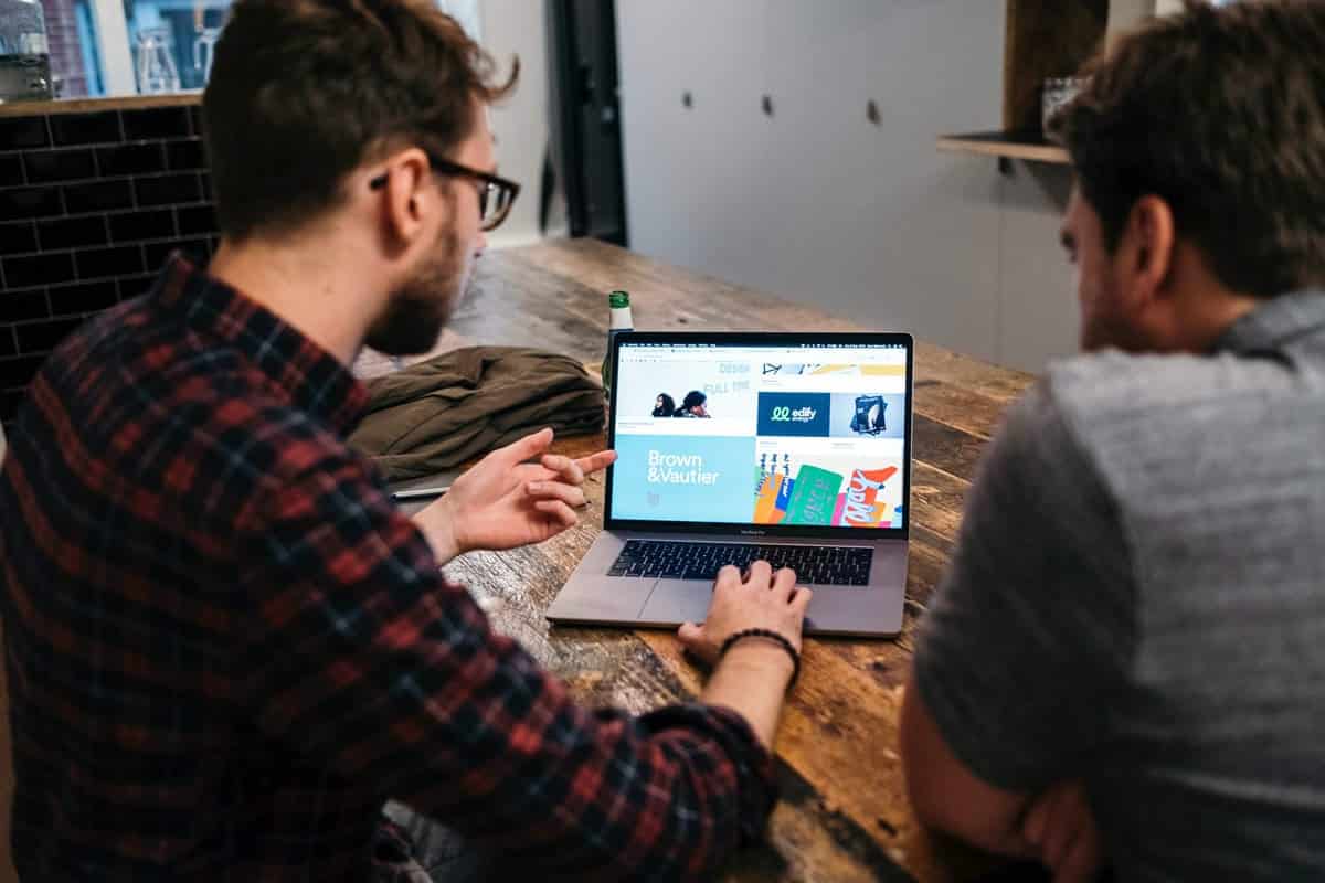 An image of two men working together on a computer.