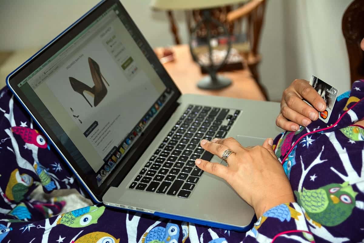 A photo of a woman holding her credit card, ready to purchase shoes online.