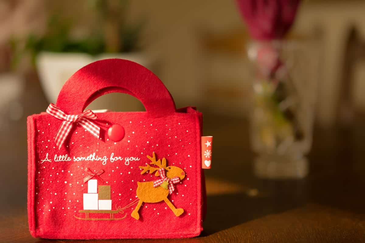 A photo of a red felt gift bag with a reindeer pulling a sledge full of presents.