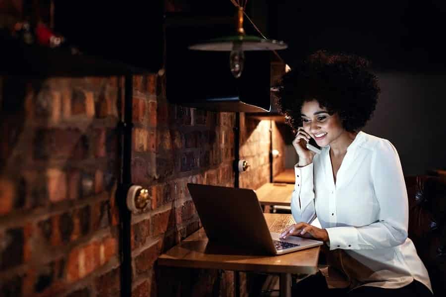 A photo of a woman taking a work call in the evening.