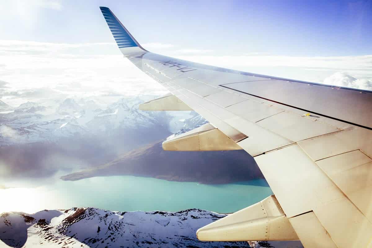 An image of a plane flying through the clouds and snowy mountains.