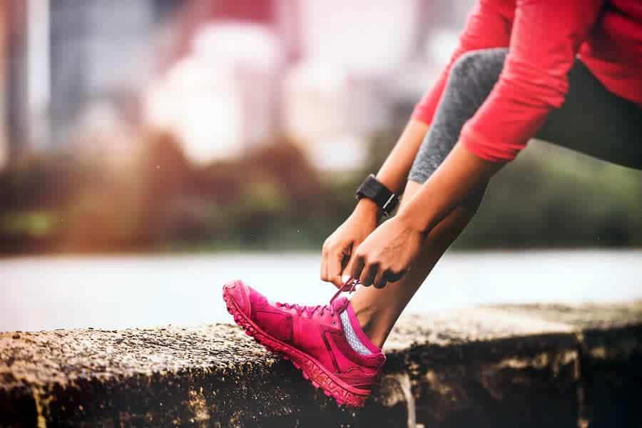 A photo of a woman lacing up her shoes before a run.