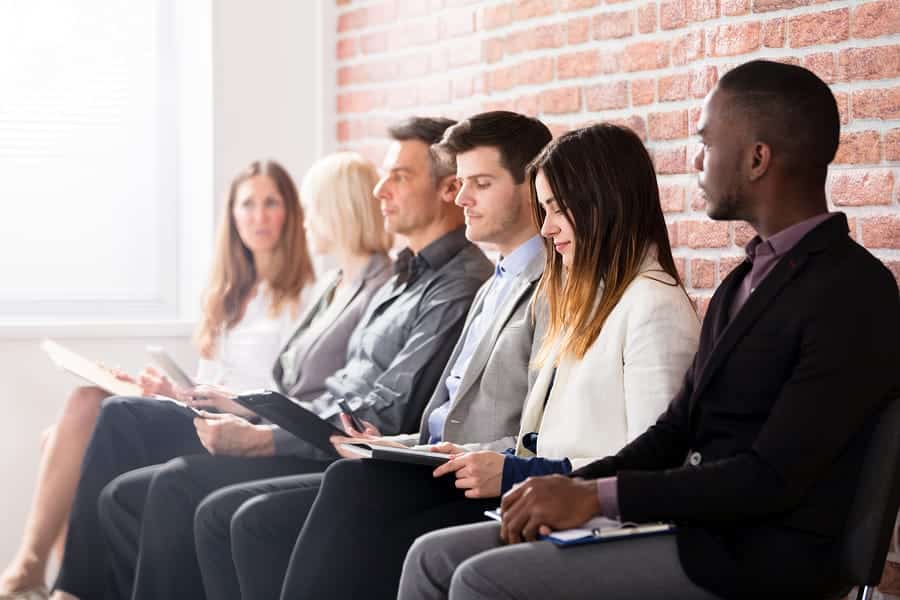 A photo of multiple job applicants sitting in a waiting area before their interviews.