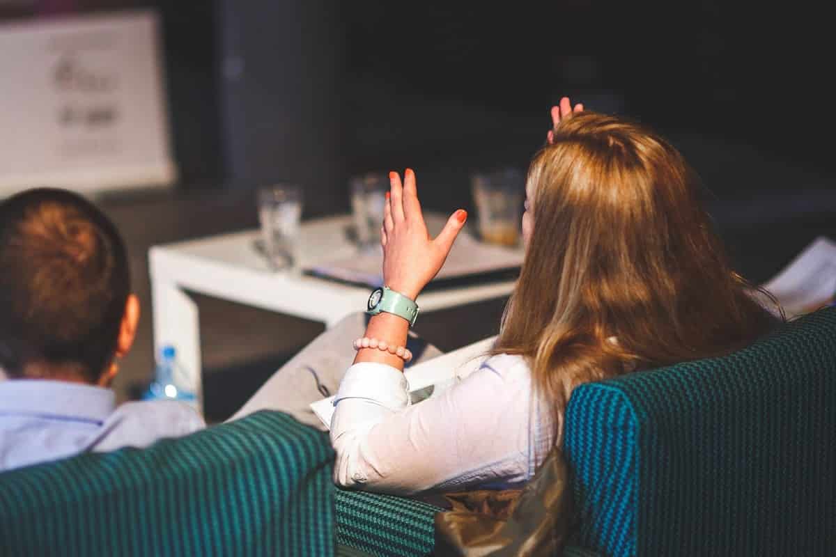 An image of two people in a meeting. A woman is making a point and moving her hands.