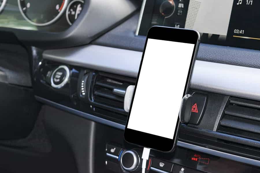 A photo of a smartphone attached to the dashboard of a car.