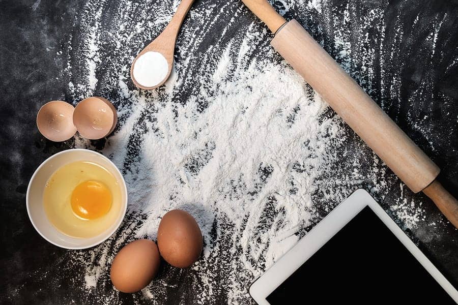 A photo of baking supplies next to an iPad on a kitchen counter.