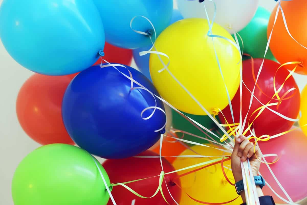 An image of a person holding a large bunch of multicolored balloons.