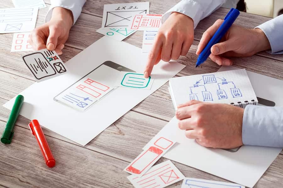 A photo of mobile app designers drawing out wireframes.