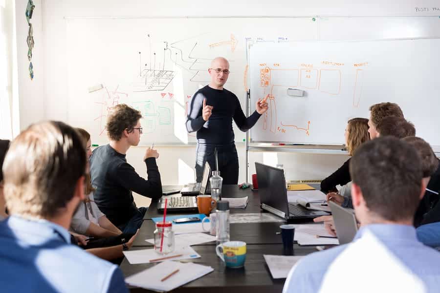 A photo of a man using a dry erase board to demonstrate an idea.