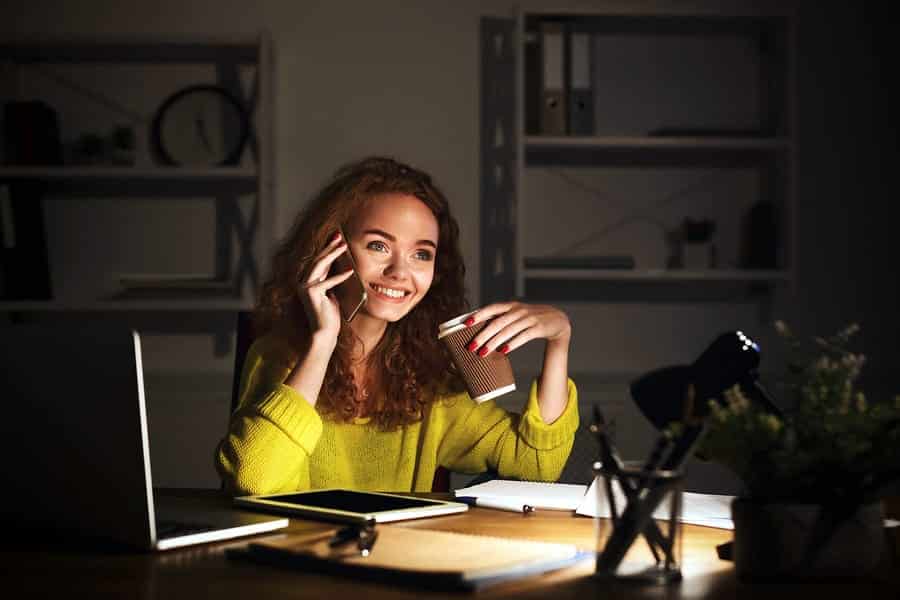 A photo of a woman working at her desk late into the evening.