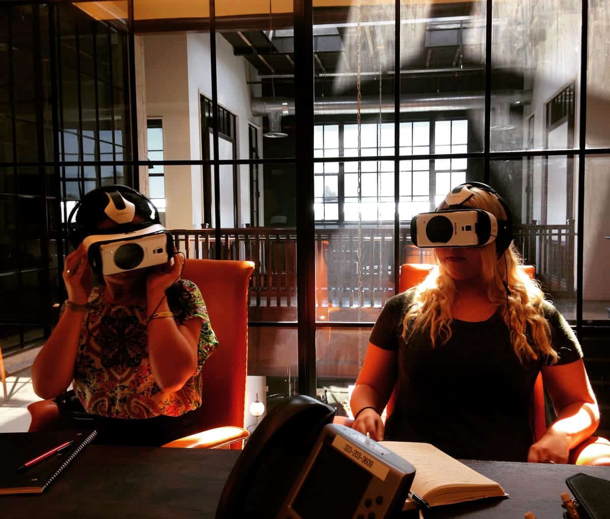 A photo of two women wearing virtual reality headsets in an office.