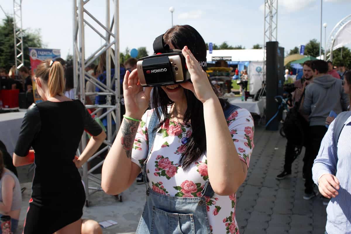 A photo of a woman wearing a VR headset outdoors at a festival.