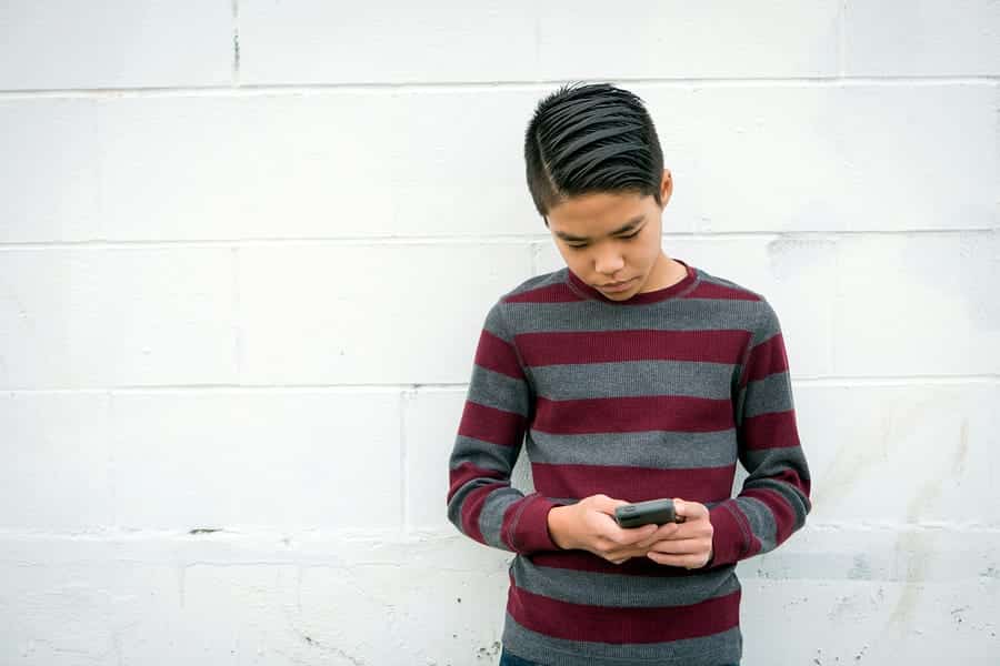 A photo of a teenage boy looking at his smartphone.