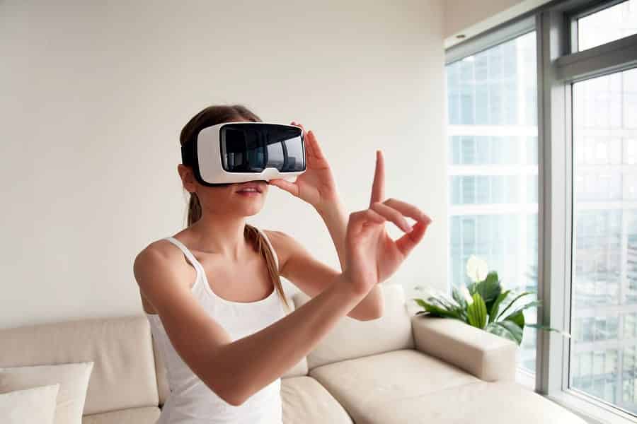 A photo of a woman wearing a virtual reality headset, holding a finger up to touch something we can’t see.