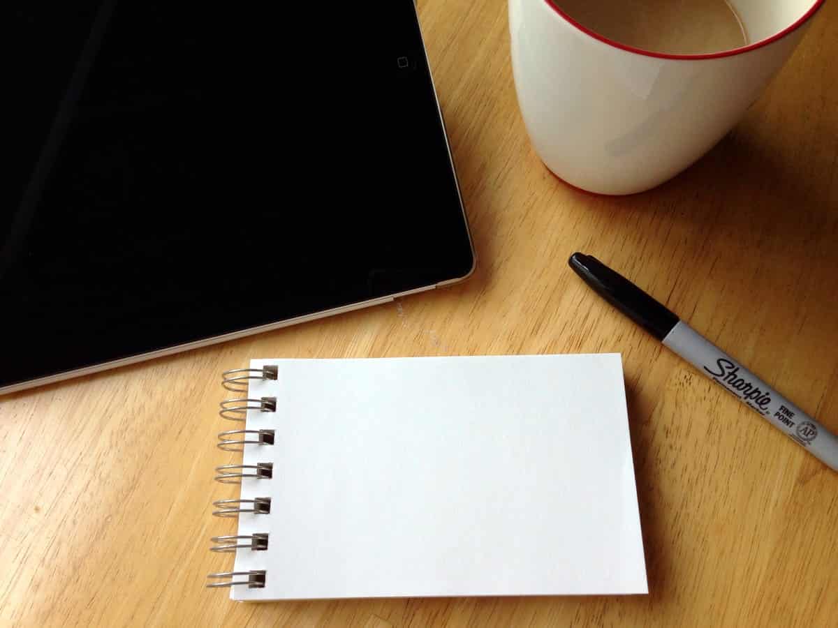 A photo of a tablet and a small sketchpad on a freelance designer’s desk.