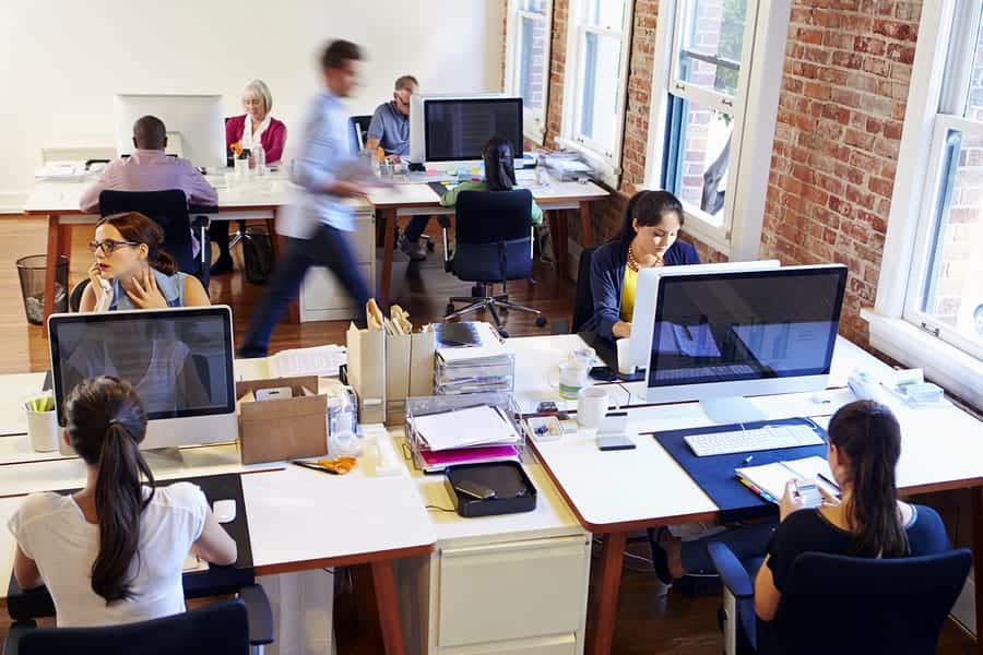 A photo of multiple mobile app developers working hard in an office.