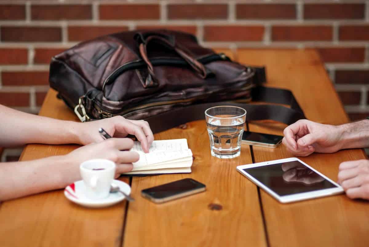 An image of two coworkers meeting informally over coffee at a wooden table.