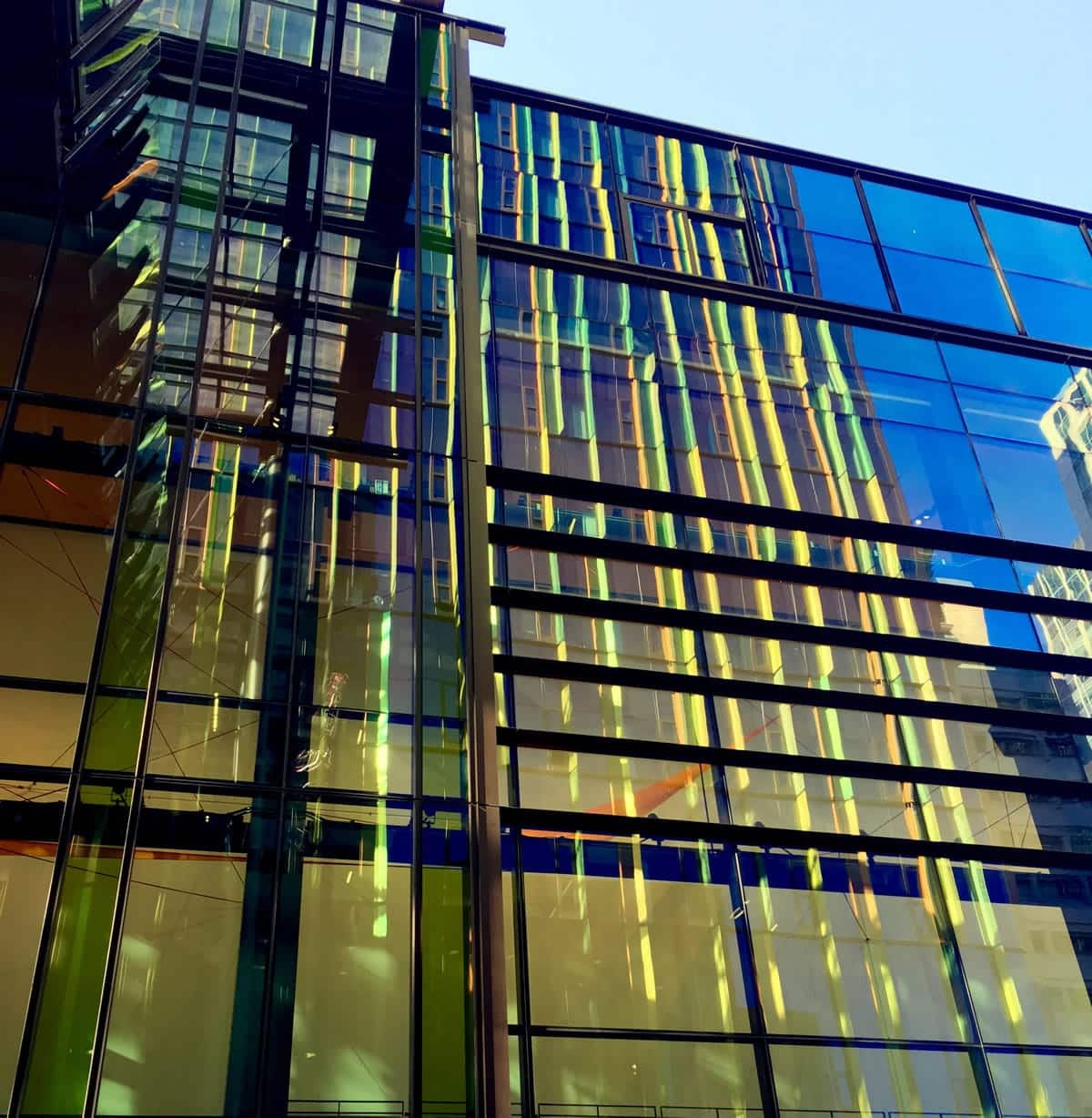 A photo of a glass building with colored lights reflecting off of it.