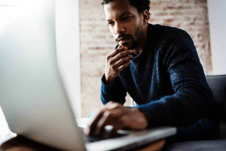 A photo of an entrepreneur working on his laptop at his apartment.