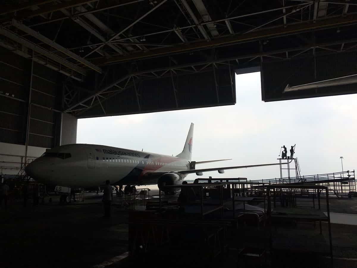 A photo of a large airplane being maintenance in an airplane hangar.