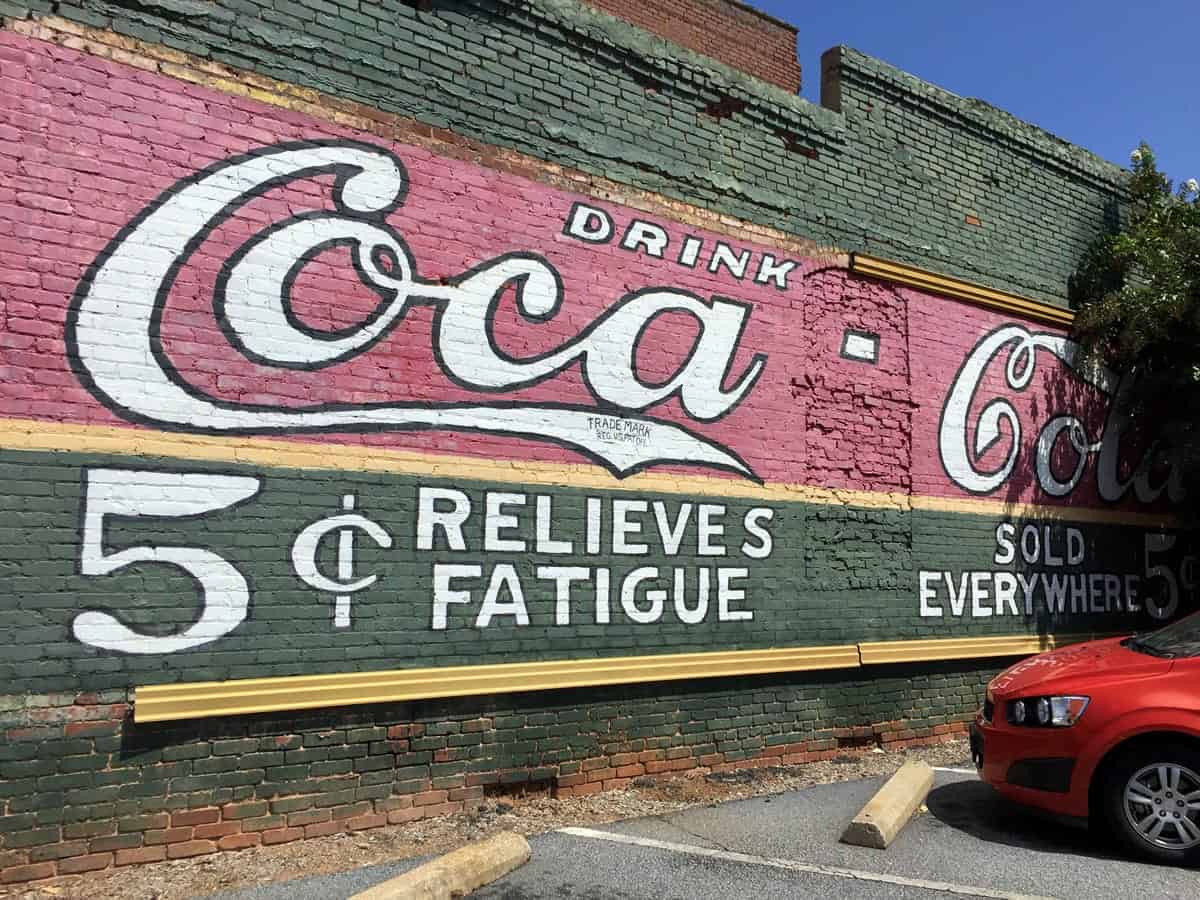 A photo of an old Coca-Cola ad painted on a brick building.