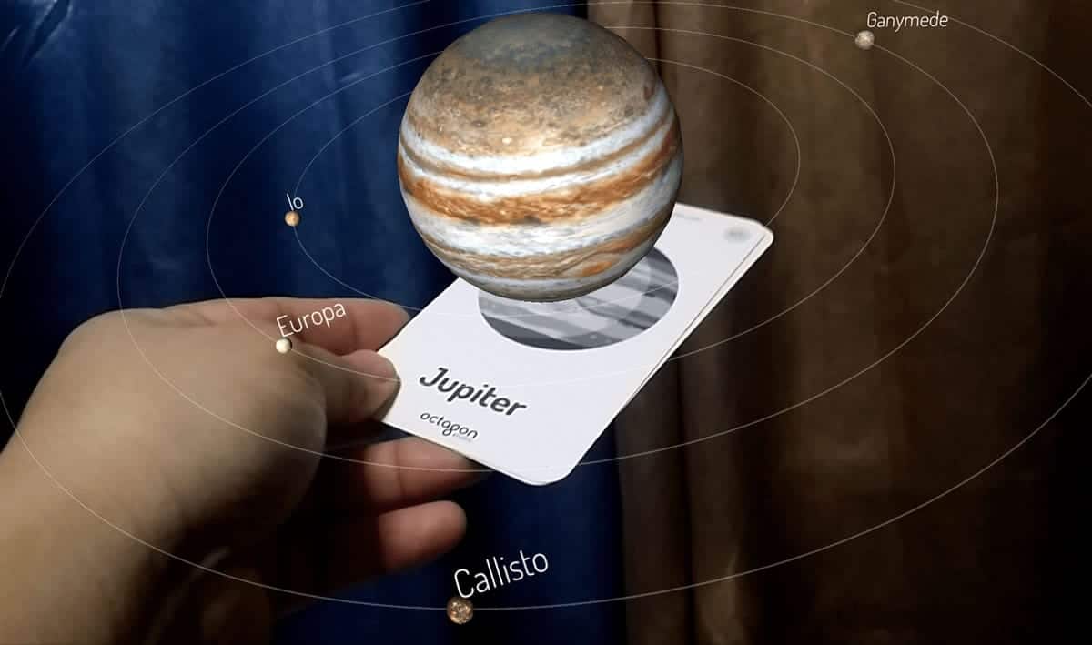 A photo of a 3D augmented reality model of the planet Jupiter coming out of a card.