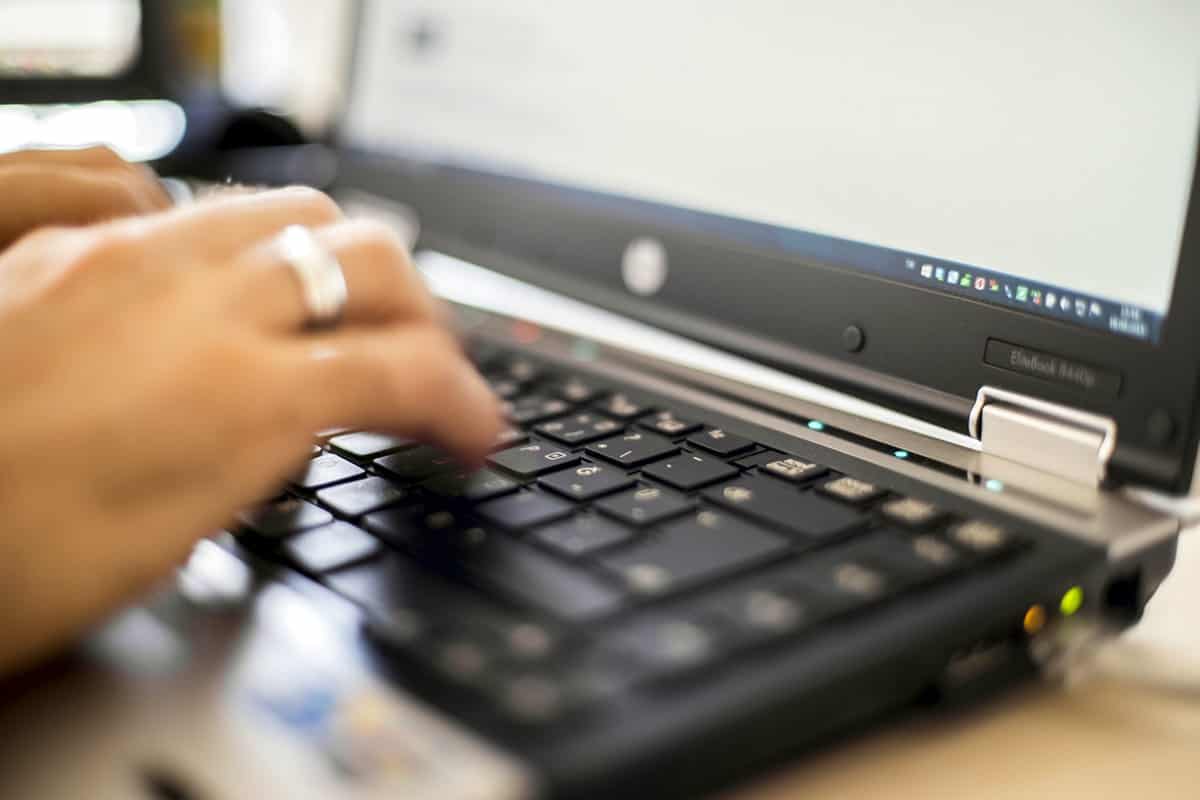 A close-up photo of a graphic designer’s hands typing on her laptop.