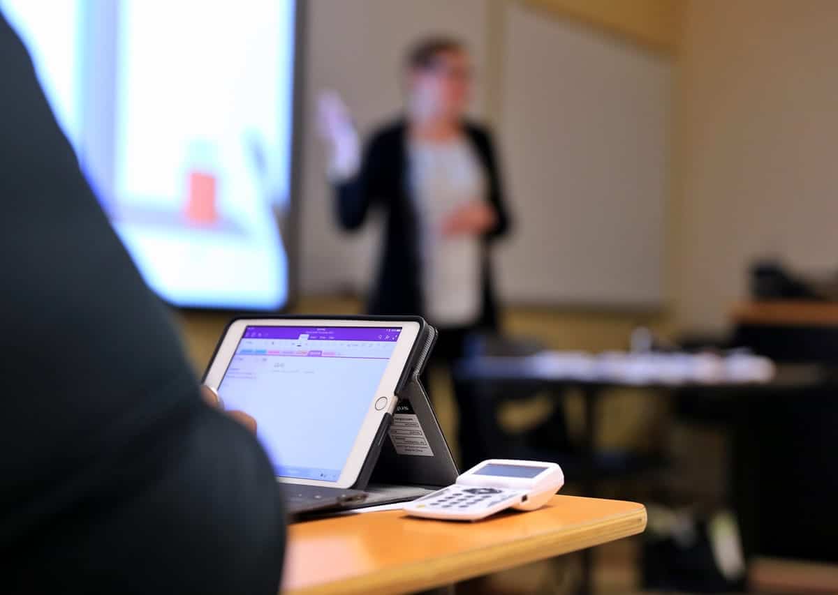 A photo of a person taking notes on a tablet during a presentation.